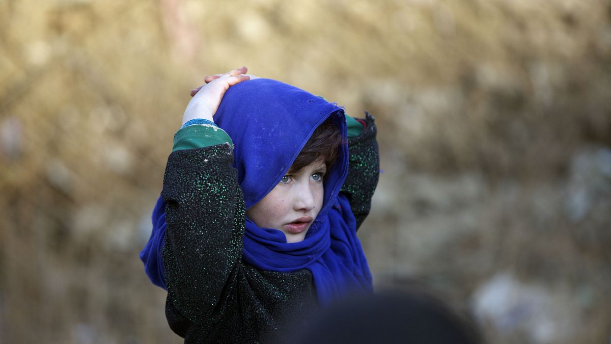 Afganistan'ın başkenti Kabil'de bir yardım kuruluşu tarafından dağıtılan gıda yardımını alan bir kız çocuğu babasını beklerken