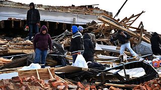 A family digs through the remains of their apartment in Mayfield, Ky., Saturday, Dec. 11, 2021. 