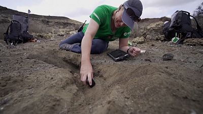 An ESA trainee asatronaut examines rock samples from Earth as part of a training programme for future Mars or lunar missions.