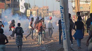 متظاهرون سودانيون ينظرون إلى قوات الأمن وهي تطلق قنابل الغاز المسيل للدموع لتفريق حشد في العاصمة الخرطوم ، في 6 ديسمبر 2021.