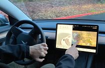 Vince Patton, a new Tesla owner, demonstrates on Wednesday, Dec. 8, 2021, on a closed course in Portland, how he can play video games on the vehicle's console while driving.