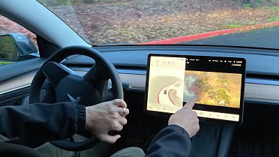 Vince Patton, a new Tesla owner, demonstrates on Wednesday, Dec. 8, 2021, on a closed course in Portland, how he can play video games on the vehicle's console while driving.