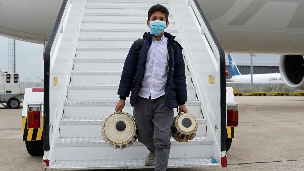An Afghan boy carrying musical instruments disembarks from an airplane at Lisbon military airport