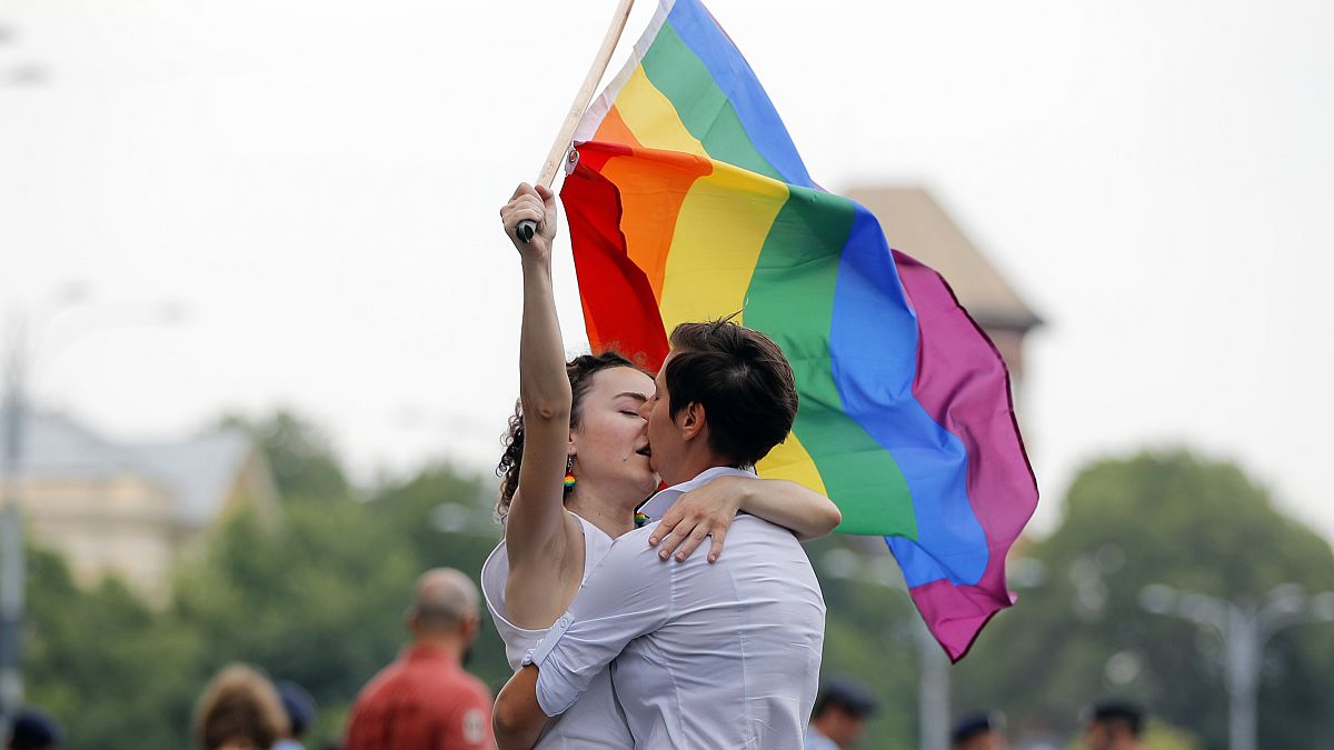 In this Saturday, June 9, 2018 file photo, two girls kiss holding a rainbow flag during the gay pride parade in Bucharest, Romania. 