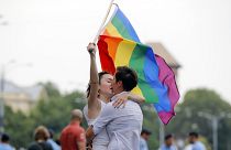 In this Saturday, June 9, 2018 file photo, two girls kiss holding a rainbow flag during the gay pride parade in Bucharest, Romania. 