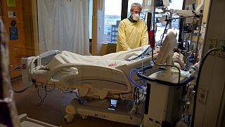 Steve Grove, a chaplain at Hennepin County Medical Center, prays in a COVID-19 patient's room, Friday, Dec. 10, 2021, in Minneapolis.