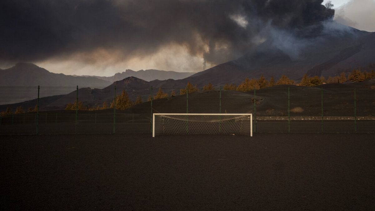 Un campo de fútbol está cubierto por cenizas negras mientras la lava fluye desde el volcán, en la isla canaria de La Palma, España, el lunes 6 de diciembre de 2021