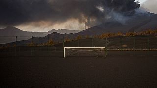 Un campo de fútbol está cubierto por cenizas negras mientras la lava fluye desde el volcán, en la isla canaria de La Palma, España, el lunes 6 de diciembre de 2021
