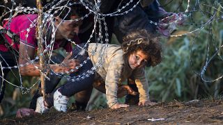 Egy gyereket segítenek át Szerbiából Magyarországra a szögesdrót kerítésen át Röszkénél