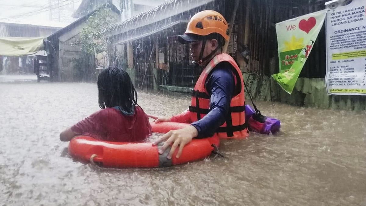 Спасатель помогает девочке в городе Кагаян-де-Оро, Филиппины 16.12.2021
