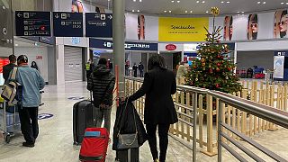 Arriving passengers walk by a Christmas tree at Paris Charles de Gaulle airport terminal E Tuesday Dec. 22, 2020. 