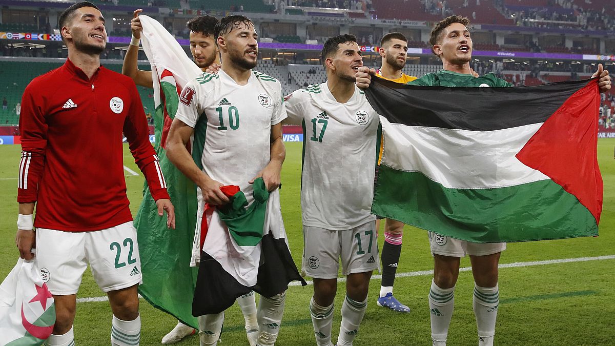 اعبو منتخب الجزائر يلوحون بالعلم الوطني الفلسطيني والجزائري بعد فوزهم في مباراة نصف نهائي كأس العرب 2021 ضد قطر على ملعب الثمامة، الدوحة، الأربعاء 15 ديسمبر 2021