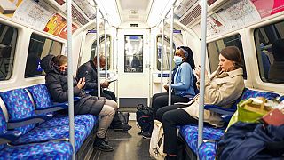 Emberek a londoni metróban, egyesek maszkkal, mások anélkül. Az Egyesült Királyságban a legmagasabb az igazolt omikron-fertőzöttek száma