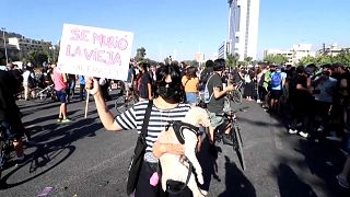 Una mujer sostiene una pancarta que lee "se murió la vieja" por la muerte de Lucía Hiriart, 16/12/2021, Santiago, Chile