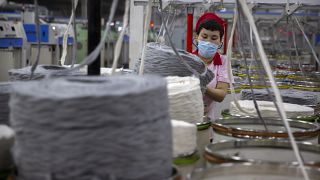 عامل يجمع خيوطا قطنية بمصنع نسيج في أكسو بمنطقة شينجيانغ غرب الصين