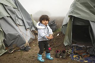 A young boy poses for a photograph at a makeshift camp for migrants, mostly from Afghanistan, in Velika Kladusa, Bosnia, October 2021