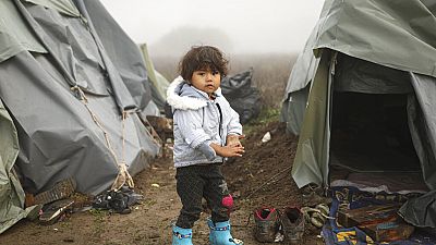 A young boy poses for a photograph at a makeshift camp for migrants, mostly from Afghanistan, in Velika Kladusa, Bosnia, October 2021