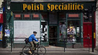 In this Tuesday, April 5, 2016 file photo, a man cycles past a Polish Specialties shop in London.