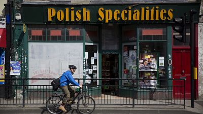 In this Tuesday, April 5, 2016 file photo, a man cycles past a Polish Specialties shop in London. 