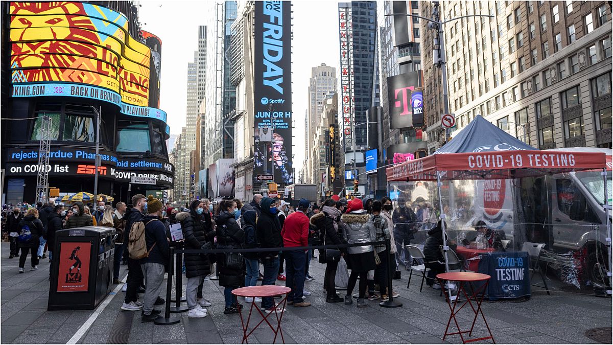 أشخاص يقوفون في طابور أمام مركز صحي متنقل في ساحة تايمز بمدينة نيويورك الأمريكية  لإجراء اختبار الإصابة بـ"كوفيد-19"، الجمعة، 17 ديسمبر، 2021 .