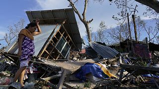 A resident salvages parts of her home damaged due to Typhoon Rai in Talisay, Cebu province, central Philippines