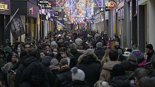Crowds of people walk down a street on the last Saturday before Christmas in Amsterdam, the Netherlands