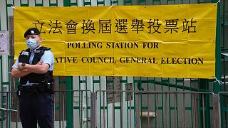 A police officer stands guard outside a polling station in Hong Kong Sunday, Dec. 19, 2021.