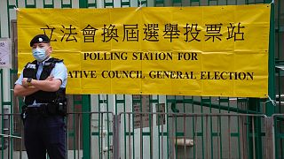 A police officer stands guard outside a polling station in Hong Kong Sunday, Dec. 19, 2021. 