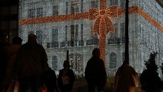 People walk in front of a Christmas decorated electronic store at Syntagma square in Athens, Greece