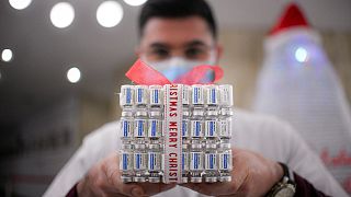 A member of the medical staff at a COVID-19 vaccination center holds a present box made of empty vaccine containers in Bucharest, Romania, Dec. 6, 2021.