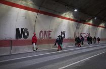 Migrants headed to France from Italy walk past graffiti that reads "No One is Illegal" in a tunnel leading to the French-Italian border, Saturday, Dec. 11, 2021.