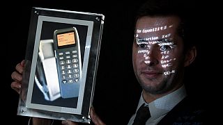Maximillien Aguttes, de la maison de vente aux enchères Aguttes, présente un écran montrant un téléphone avec le tout premier SMS au monde
