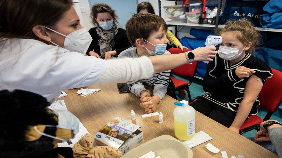A medical staff takes the temperature to a child in a vaccine center in Sélestat, eastern France, Dec. 21, 2021. 