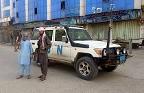 Afganistan'ın kuzeyindeki Kunduz kentinde bir BM aracı önünde poz veren Taliban savaşçıları (arşiv) 