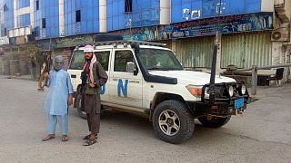 Afganistan'ın kuzeyindeki Kunduz kentinde bir BM aracı önünde poz veren Taliban savaşçıları (arşiv)
