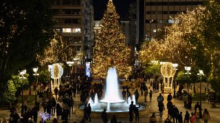Menschen flanieren auf dem weihnachtlich geschmückten Syntagma-Platz in Athen
