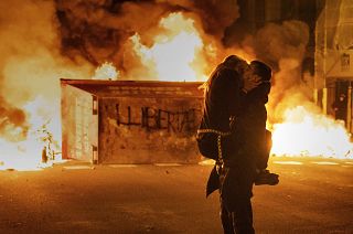 A couple kiss during clashes with police following a protest condemning the imprisonment of rap singer Pablo Hasél in Barcelona, Spain. February 2021