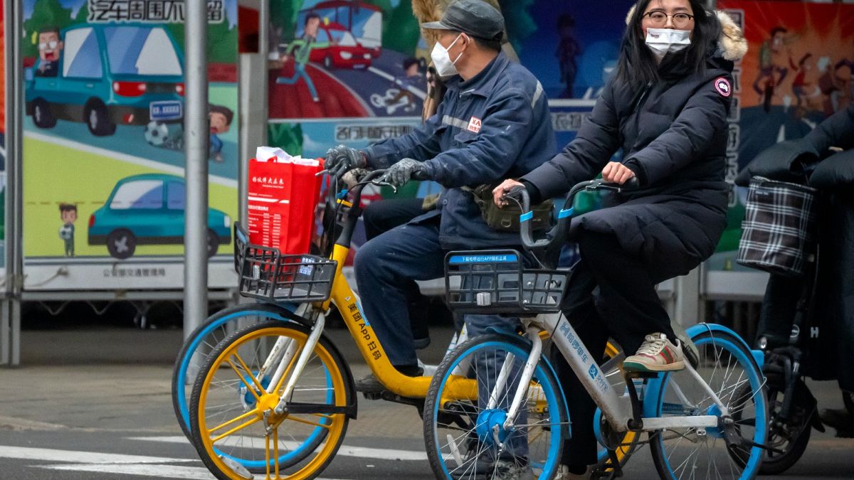 Bicyclists wearing face masks to protect against COVID-19 wait at an intersection in the central business district in Beijing, Dec. 23, 2021. 