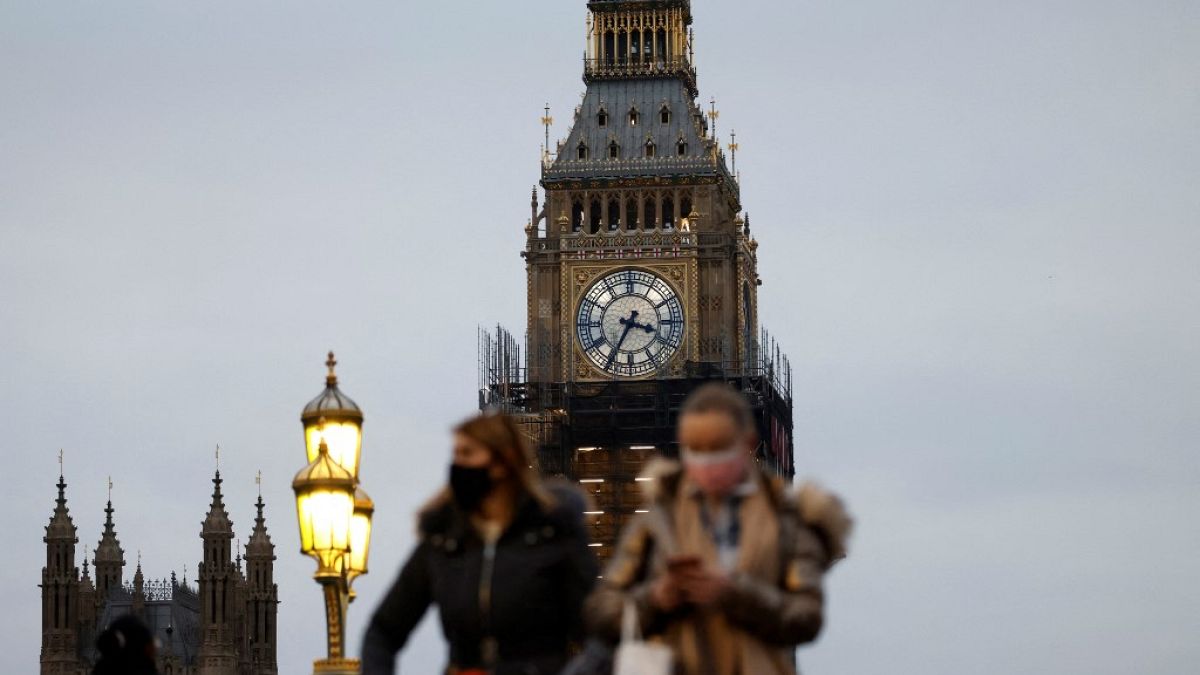 People walk past the Big Ben clock at the Houses of Parliament in central London on December 16, 2021 as some scaffolding is removed with restoration project nearing its end.