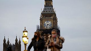 People walk past the Big Ben clock at the Houses of Parliament in central London on December 16, 2021 as some scaffolding is removed with restoration project nearing its end.
