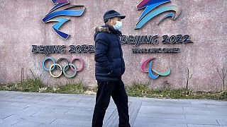 Ein Mann vor den Logos der Olympischen und Paralympischen Spiele 2022