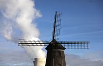 بخار يتصاعد من محطة للطاقة النووية خلف طاحونة هوائية قديمة على نهر شيلدت في دويل، بلجيكا.