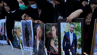 أقارب ضحايا انفجار 4 آب/أغسطس 2020 في مرفأ بيروت يضيئون الشموع ويحملون صوراً لأحبائهم في بيروت، لبنان.