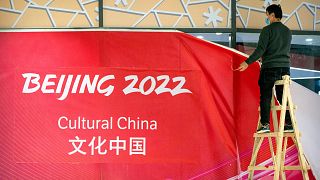 A worker takes down coverings around an exhibit on Chinese culture at a commercial plaza at the Winter Olympic Village in Beijing, Friday, Dec. 24, 2021.