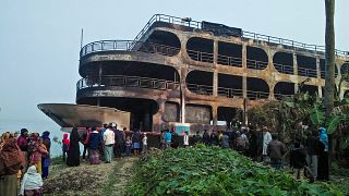 Villagers look at a burnt-out ferry after it caught on fire killing at least 37 people in Jhakakathi, 250 kilometres south of Dhaka, on December 24, 2021.