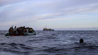 A migrant who was aboard a precarious rubber boat with others jumps to the water as they are rescued around 35 miles away from Libya, in Libyan SAR zone, Oct. 18, 2021