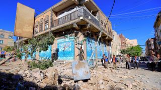 يمنيون يتفقدون ما خلفته الغارة الجوية للتحالف بقادة السعودية على العاصمة صنعاء ليل الجمعة. 24/12/2021