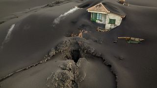 A fissure is seen next to a house covered with ash on the Canary island of La Palma, Spain, Dec. 1 2021.