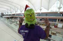 Гринчу здорово помог омикрон: работник аэропорта в маске похитителя Рождества встречает пассажиров, чьи рейсы отменены в последнюю минуту