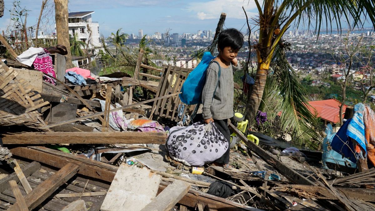 طفل يبحث عن ممتلكاته بعد تضرر المنزل بسبب إعصار راي في مقاطعة سيبو بوسط الفلبين.
